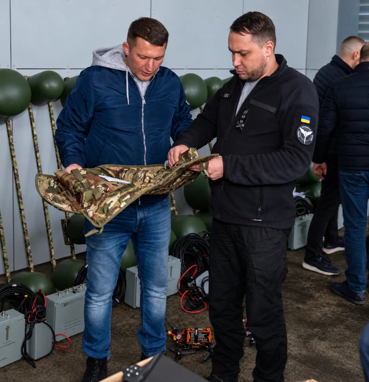 Двоє чоловіків оглядають камуфляжний чохол для обладнання