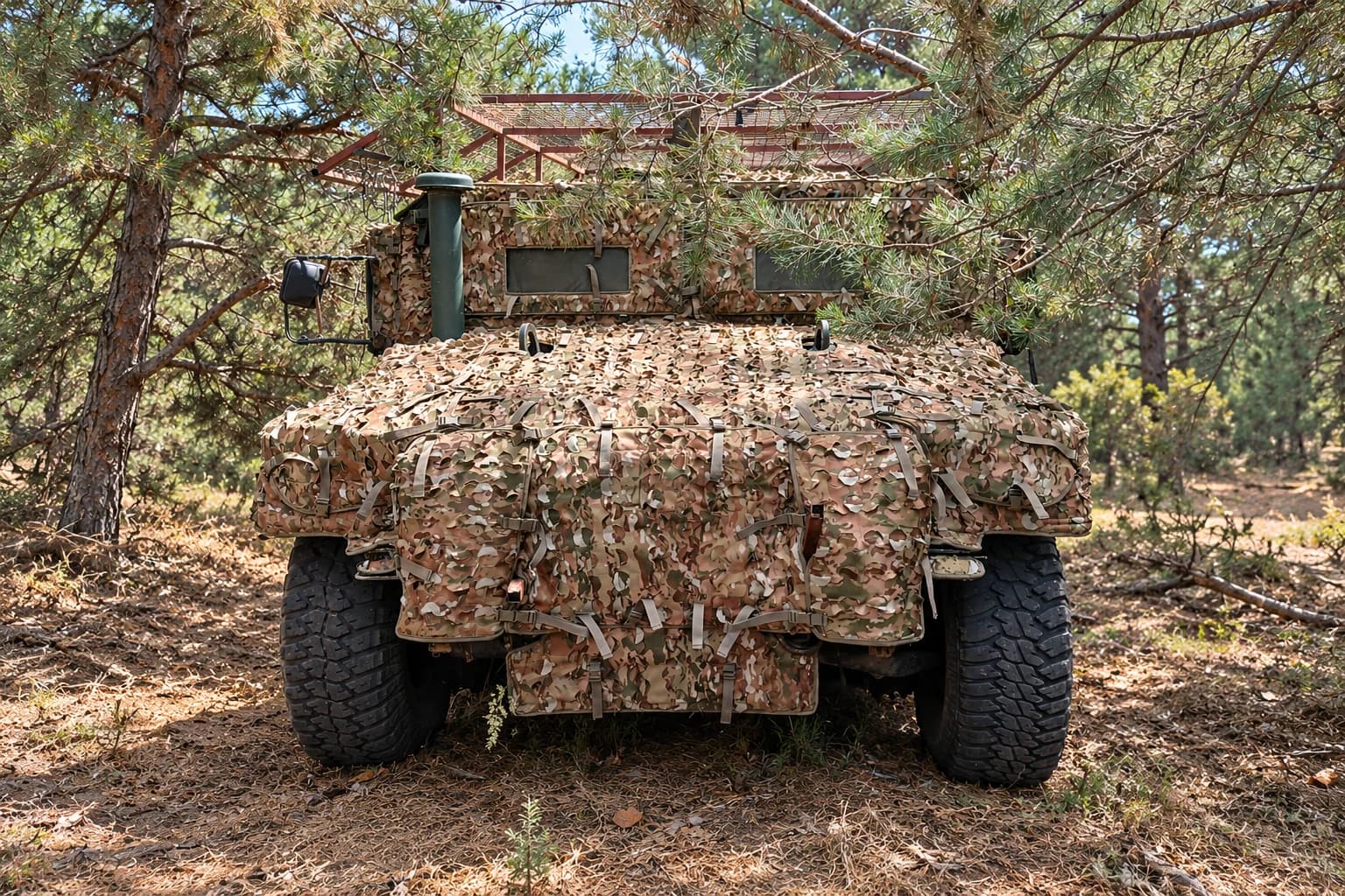 Бронеавтомобіль HMMWV у маскувальному покритті серед сосен