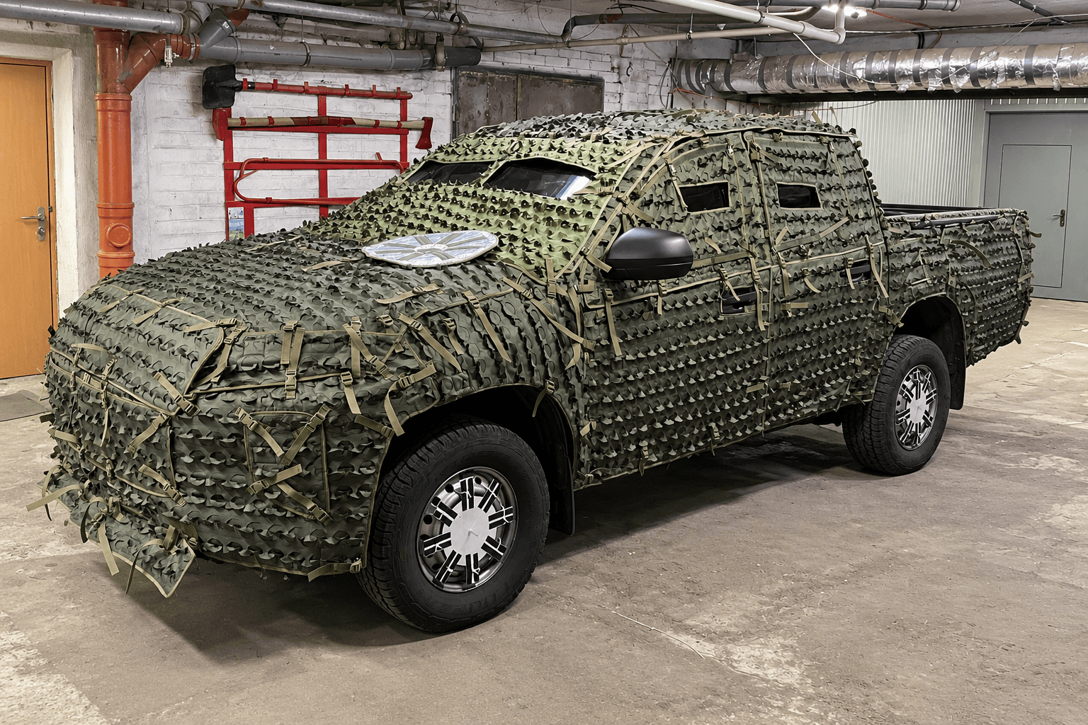 Mitsubishi L200 із камуфляжним покриттям у гаражній майстерні